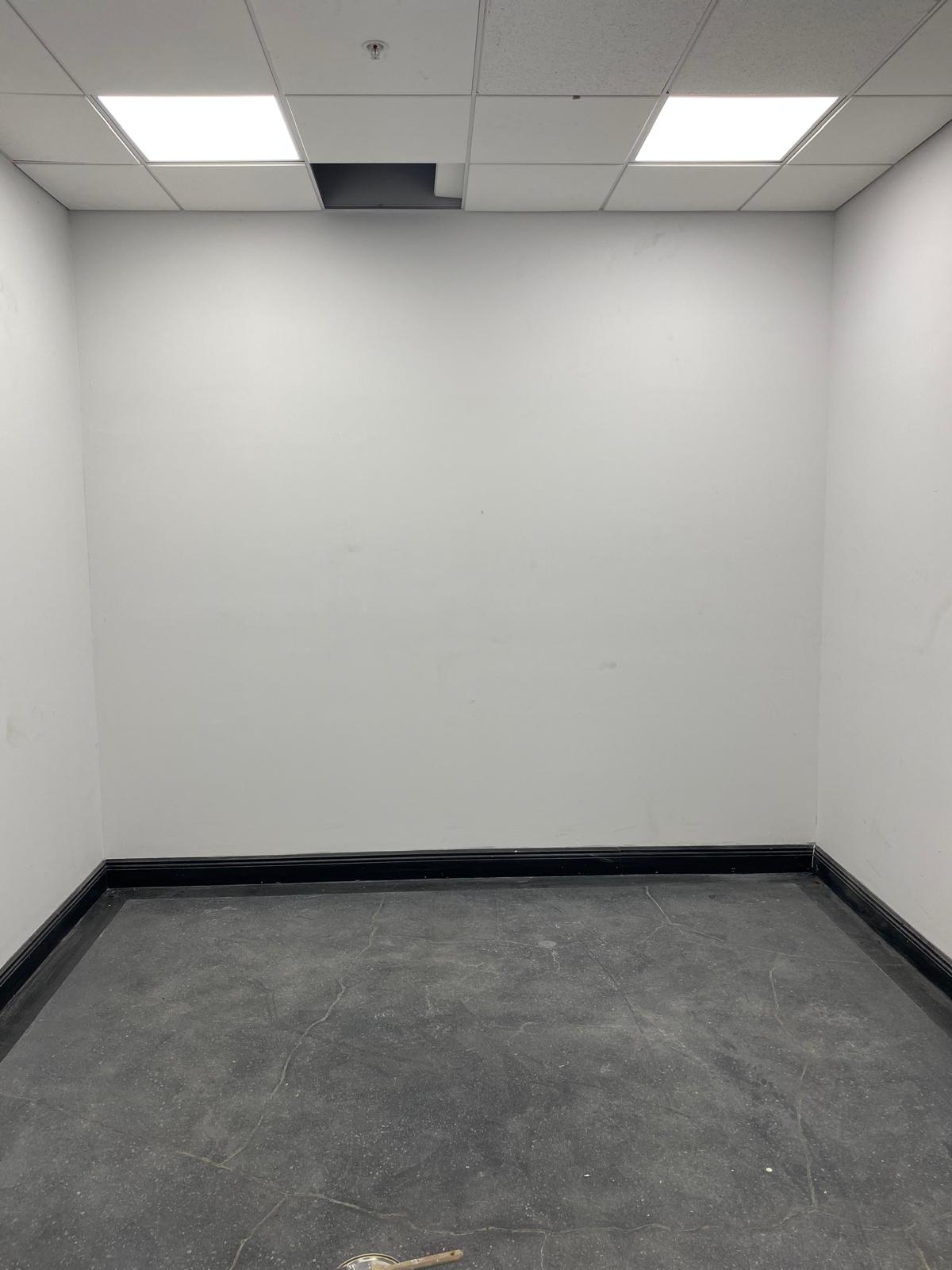 Freshly painted white office interior walls with drop ceiling and black baseboards in Fort Lauderdale commercial space