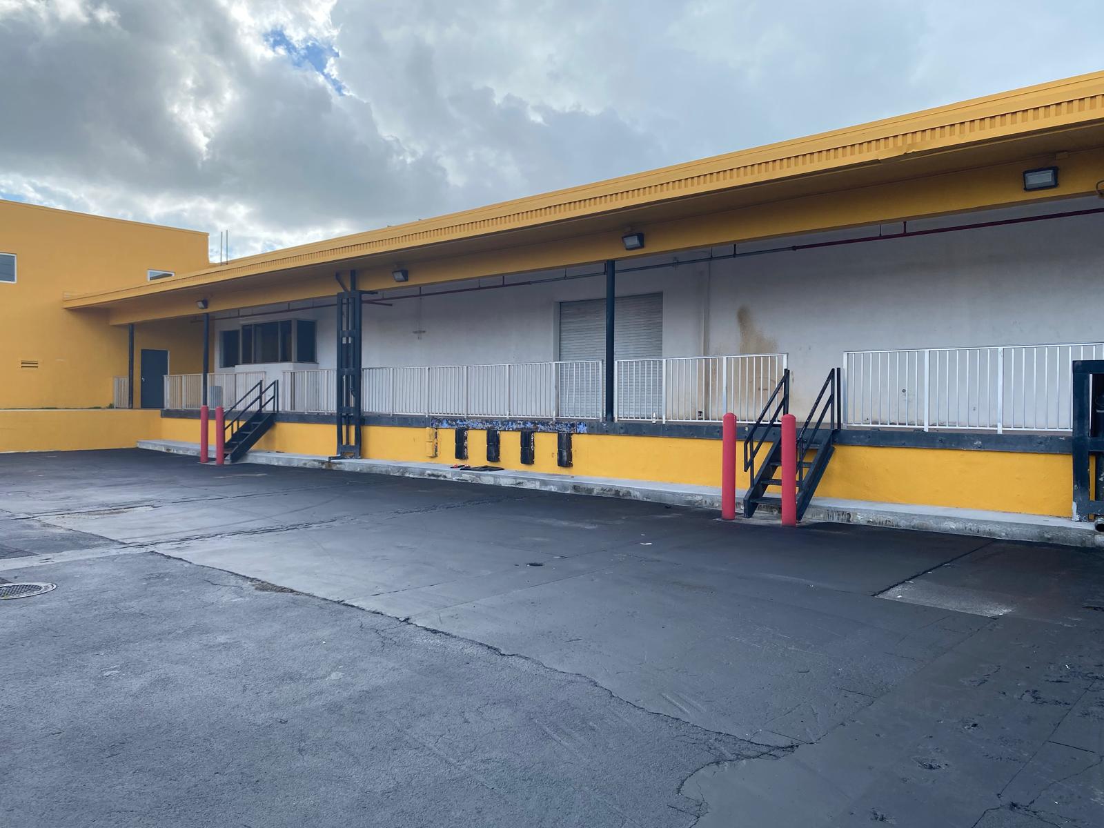 Yellow and gray commercial loading dock exterior repaint at a warehouse facility in Hialeah