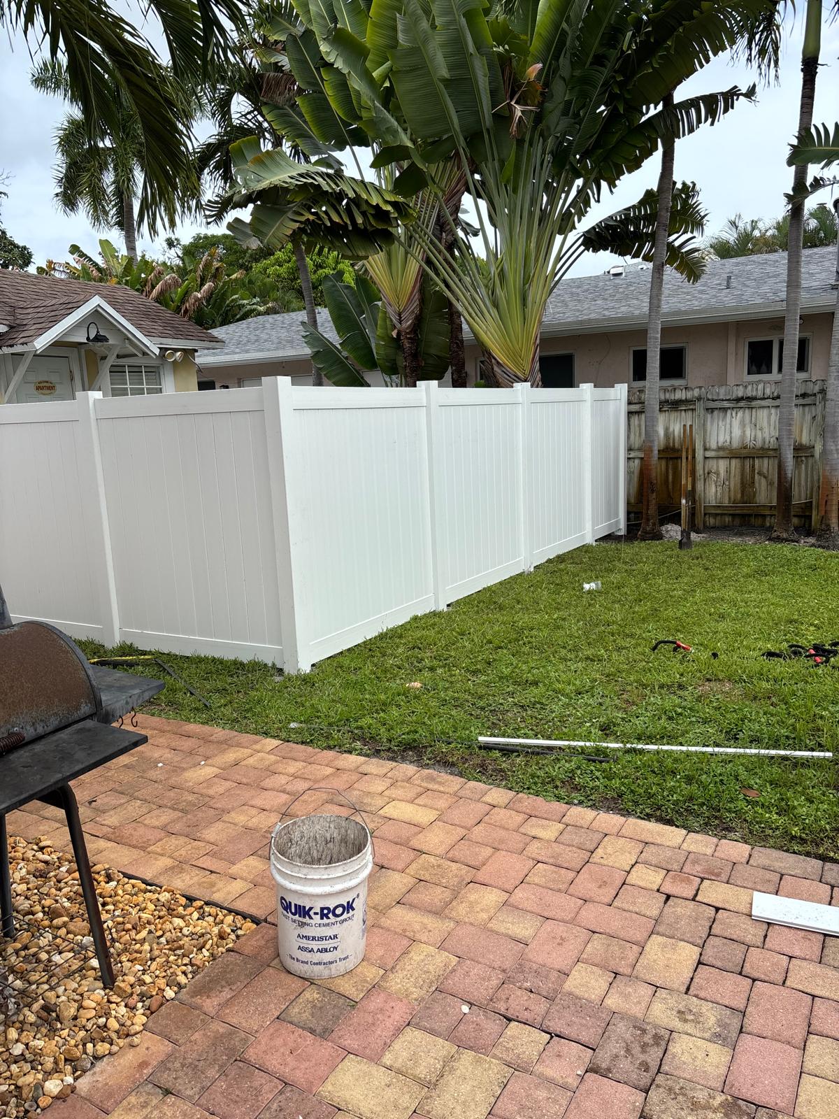 Freshly painted white vinyl privacy fence in a Hollywood Florida backyard with tropical palms