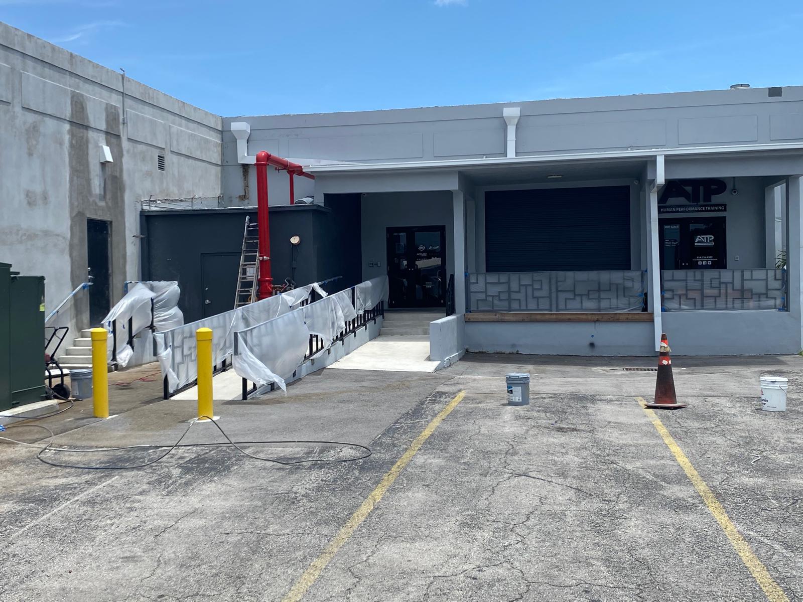 Commercial warehouse loading ramp with masked railings and plastic sheeting prepped for exterior painting in Fort Lauderdale