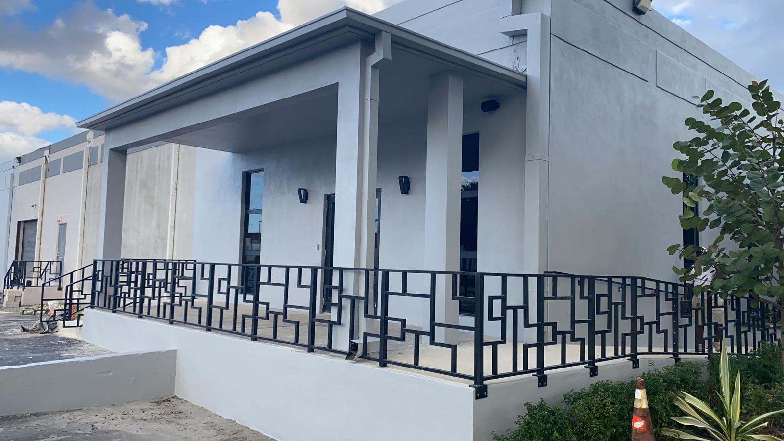 Freshly painted light gray commercial building entrance with decorative black metal railing in Doral Florida